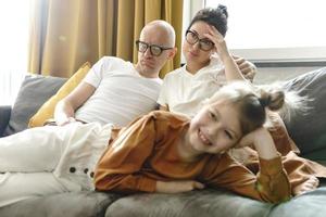 gelukkig weinig meisje aan het kijken tekenfilms met haar moe ouders foto