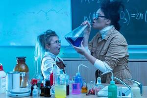 leraar en weinig meisje gedurende chemie les menging Chemicaliën in een laboratorium foto