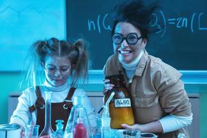 leraar en weinig meisje gedurende chemie les menging Chemicaliën in een laboratorium foto