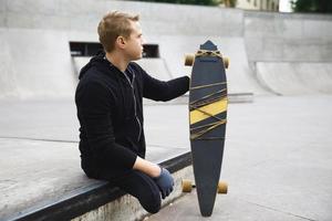 jong gehandicapten vent met een longboard in een skatepark foto