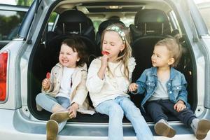 weinig kinderen zittend in een auto's romp voordat een weg reis foto
