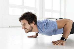 Mens aan het doen Opdrukken gedurende gymnastiek training in de Sportschool foto