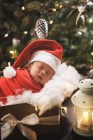 schattig pasgeboren baby vervelend de kerstman claus hoed is slapen in de Kerstmis geschenk doos foto