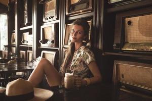 jong gelukkig vrouw drinken bevroren koffie in elegant retro cafe foto