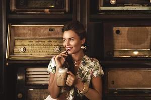 jong gelukkig vrouw drinken bevroren koffie in elegant retro cafe foto