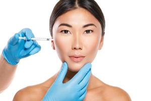 Aziatisch vrouw gedurende jukbeen modulatie of vulmiddel injectie procedure foto