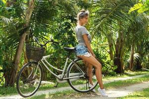 sexy en mooi vrouw met een fiets in de tropisch tuin foto
