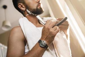 Mens scheren zijn baard met een Rechtdoor scheermes foto