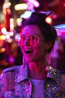 elegant vrouw vervelend jasje met schijnend pailletten Aan de stad straat met neon lichten foto