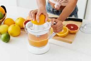 vrouw handen en citrus sapcentrifuge gedurende vers oranje sap voorbereiding foto