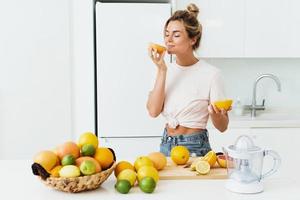 mooi vrouw snuiven vers oranje gedurende citrus sap voorbereiding Bij huis foto