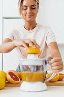 jong mooi vrouw voorbereidingen treffen oranje sap met modern citrus sapcentrifuge machine foto