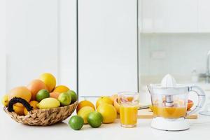 glas van oranje sap, citrus sapcentrifuge en divers citrus fruit Aan keuken tafel foto