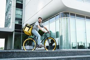 uitdrukken levering koerier staand Aan fiets met geïsoleerd tas. foto