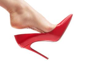 vrouw voet met rood stiletto hakken schoen Aan wit achtergrond foto