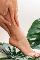 nat vrouw voeten met glad huid en monstera deliciosa tropisch blad foto