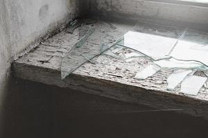 vensterbank met spin web en gebroken glas in verlaten gebouw. foto