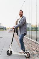 jong vrolijk Mens rijden zijn e-scooter Aan de stad straat foto