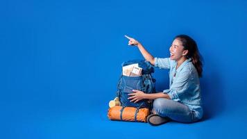 jonge Aziatische reiziger gelukkige vrouw in blauw shirt met rugzak met en uitrusting voor reizigers vakantie met een kaart, op blauwe kleur achtergrond. reis rugzak foto