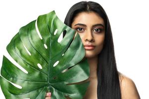 mooi Indisch vrouw met een glad huid Holding groen tropisch blad foto