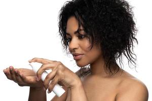 mooi zwart vrouw met een glad huid Holding fles van reiniging schuim of serum foto