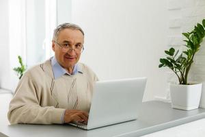 senior Mens Bij laptop betalen met credit kaart voor online boodschappen doen foto