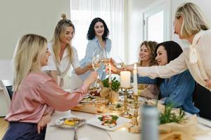 jong Dames vrienden gerinkel bril Bij de feestelijk tafel. foto