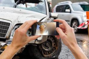 dichtbij omhoog hand- Holding smartphone en nemen foto van auto ongeluk