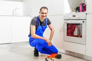 mannetje technicus zittend in de buurt oven in keuken foto