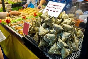 detailopname Chinese veganistisch tussendoortje voedsel ba-jang verkopen in voedsel markt voor Chinese nieuw jaar. ba-jang gemaakt met kleverig rijst- en roeren gebakken met olie verpakt in bamboe bladeren en vervolgens gestoomd. foto