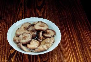 een wit bord met gepekeld champignons staat Aan een houten tafel . gezond dorp voedsel . foto