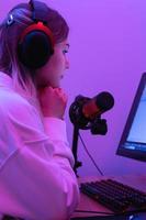 vrouw blogger gebruik makend van condensor microfoon gedurende online podcast in kamer met neon licht foto