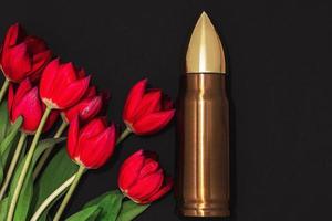 pacifisme, geweldloosheid beweging of zege dag. kogel en bundel van rood tulpen. foto