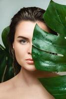 jong vrouw met een glad huid Holding monstera deliciosa fabriek blad foto