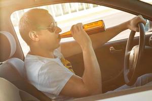 Mens is drinken bier in zijn auto foto