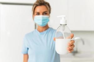 vrouw gebruik makend van hand- ontsmettingsmiddel of vloeistof zeep voor handen ontsmetting Bij huis foto