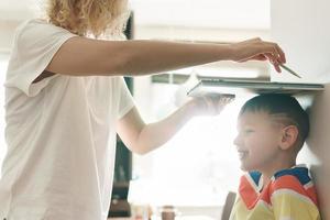 moeder speels meten de hoogte van haar zoon Bij huis foto