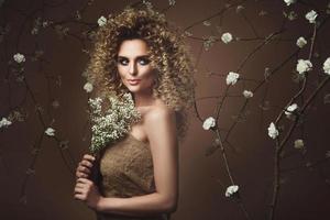 lief jong vrouw met afro kapsel en mooi bedenken met een veel van wit bloemen foto