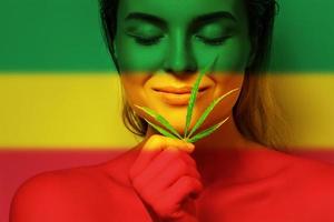 mooi vrouw met een hennep blad in kleuren van rastafari vlag foto