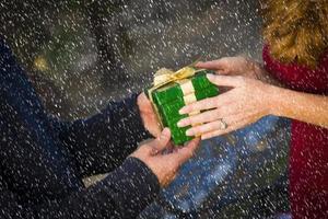 handen van Mens en vrouw uitwisselen Kerstmis geschenk in sneeuw foto