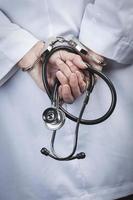 vrouw dokter of verpleegster in handboeien Holding stethoscoop foto