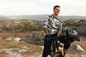 glimlachen professioneel bergafwaarts rijder en zijn fiets foto