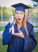 expressief jong vrouw Holding diploma in pet en japon foto