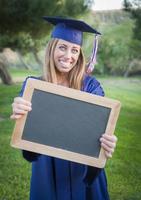 vrouw Holding diploma en blanco schoolbord vervelend pet en japon foto