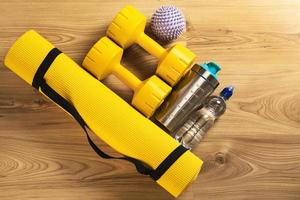 training uitrusting Aan de vloer. geel geschiktheid mat, halters, massage bal, eiwit shaker en fles van water. foto