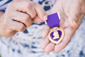 senior vrouw Holding de leger Purper hart medaille in haar handen. foto
