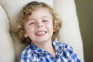 schattig blond jongen glimlachen zittend in stoel foto