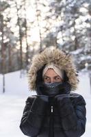 jong vrouw vervelend naar beneden jasje met een capuchon gedurende verkoudheid winter dag foto