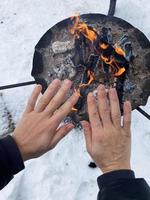 vrouw opwarming omhoog haar handen door de brand pit foto