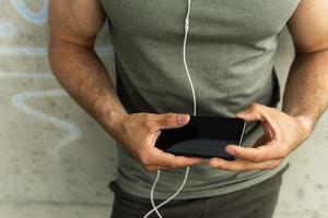 Mens Holding zwart smartphone gedurende zijn training foto